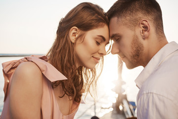 Outdoor shot of cute couple in love, closing eyes and touching with foreheads while sailing on...