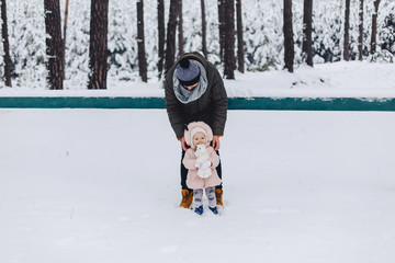 Tattoo and daughter walking with snow-covered pine forest