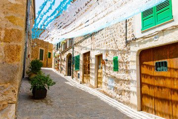 Fototapeta premium Beautiful street in Valldemossa with traditional flower decoration, famous old mediterranean village of Majorca. Balearic island Mallorca, Spain