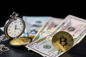 Golden bitcoin standing and retro pocket watch on us dollars with black background