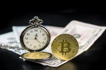 Golden bitcoin and pocket watch on us dollars standing on dark background