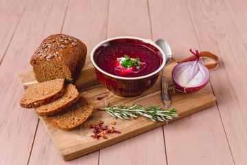 bowl of borscht with pieces of bread and onions on a wooden table