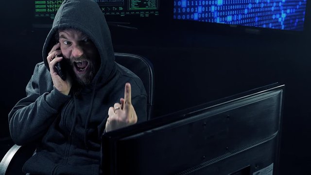 Hacker at night on the phone with partner happy and successful medium shot