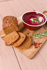 bowl of borscht with pieces of bread and onions on a wooden table