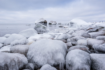 Rocky beach on wintertime. Evening light and icy weather on shore like fairy tale country. Winter on coast. Blue sky, white snow, ice covers the land on seaside. Waterside on Juminda, Estonia, Europe