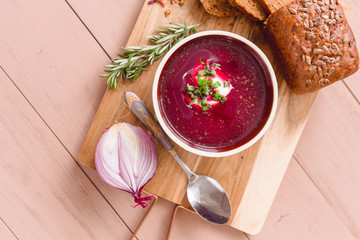 bowl of borscht with pieces of bread and onions on a wooden table