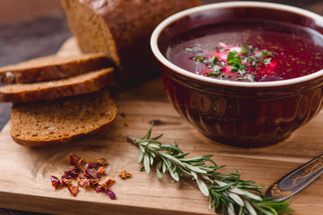 bowl of borscht with pieces of bread and onions on a wooden table