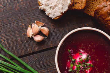 bowl of borscht with pieces of bread and onions on a wooden table