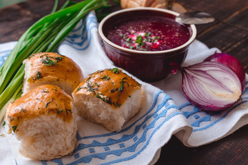 borscht with bread and onions on a wooden table