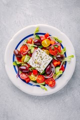 Delicious Greek salad with feta cheese, olives, tomatoes, cucumbers, paprika and red onions.