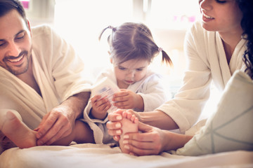 We need to massage feet to our little girl. Happy young parents.