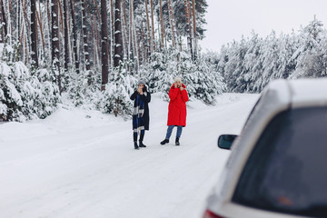 Girls in the middle of the road talking on the phone by car on a snowy road