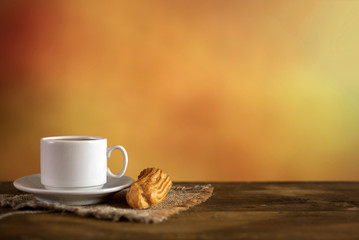 Cup of coffee with eclair on colorful background. With copy space