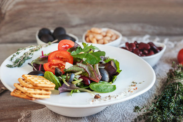 Salad diet for weight correction from the leaves of Lollo Rosso lettuce, watercress salad and other green herbs with tomatoes, olives and fitaki. Close up. Copy space.