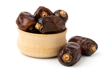Dried dates in a wooden bowl on a white.