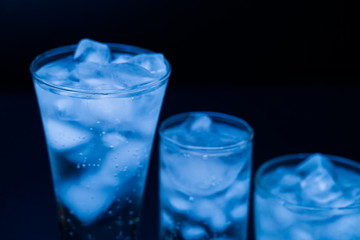 Drink. Water glass and ice, dark background