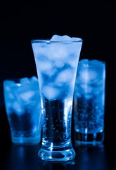 Drink. Water glass and ice, dark background