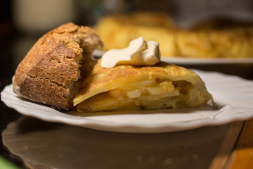 Piece of spanish omelette in a white plat  with bread and  mayonnaise