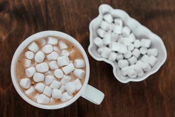 white cup with a white marshmelow on a wooden background