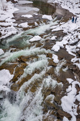 Fototapeta na wymiar Winter landscape. Mountain river flows from the rocks. Snow and mountain river