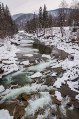 Winter landscape. Mountain river flows from the rocks. Snow and mountain river