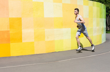 Young man running against bright wall