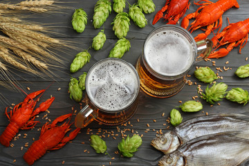 Glass beer with crawfish, dried fish and wheat ears on dark wooden background. Beer brewery concept. Beer background. top view with copy space
