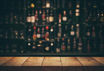 Gordijnen Leeg de bovenkant van de houten tafel met een wazige toonbank en flessenachtergrond © hakinmhan