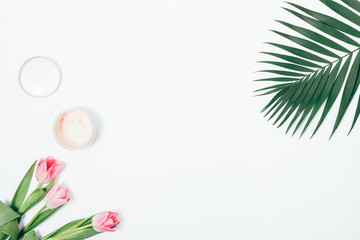 Palm branch, bouquet of pink tulips and a jar of cosmetic cream