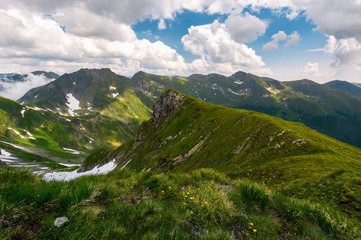 valley with snow in summer mountains. gorgeous mountainous landscape of Carpathians. rocky cliffs and grassy hillsides under a cloudy sky. Fagaras ridge of Southern Carpathian mountains, Romania