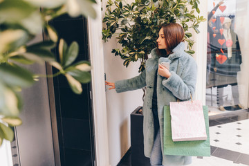 Female after shopping with bags pushing the button and call the elevator © deineka