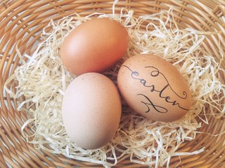 Handlettered eggs in a wicker basket for Easter celebration