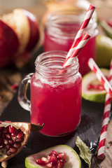 Pomegranate juice with pomegranate on a wooden board on a dark background