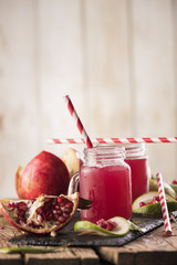 Pomegranate juice with pomegranate on a wooden board on a dark background