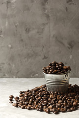Bunch of coffee beans and small bucket on dark grey background.