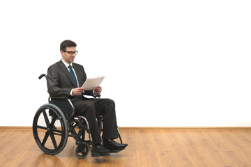 The smile disabled in a wheelchair holding papers on the white wall background