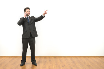 The businessman phones and gestures on the white wall background