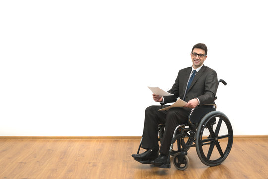 The smile man in the wheelchair holding papers on the white wall background