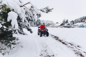A pretty girl riding a quadrocycle in a picturesque snowy area
