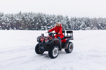 A pretty girl riding a quadrocycle in a picturesque snowy area