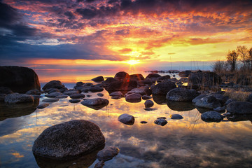 Fototapeta na wymiar colorful sunset by a lake with a rocky beach