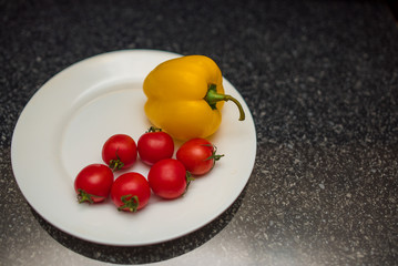 Cherry tomatoes and yellow pepper on white plate close up