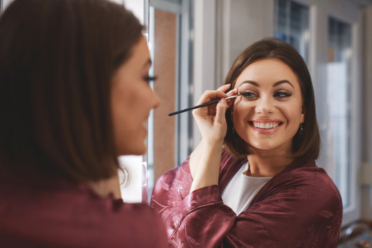 Young Woman Applying Makeup On Face At Home