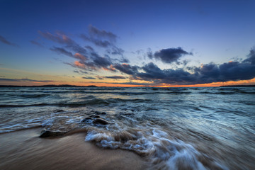 waves rushing onto a sandy beach at sunset