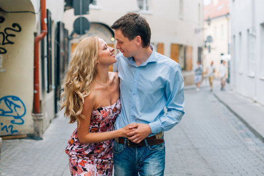 Young happy couple hugging while walking on the street. Smiling man and cheerful woman having fun in the city.
