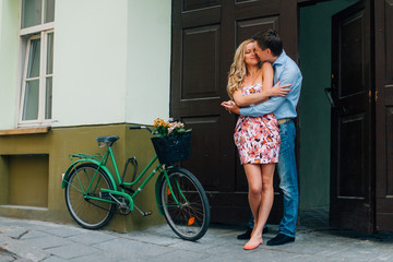 Young happy couple hugging on the street near bicycle.