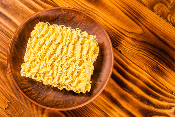 Ceramic plate with instant noodles on wooden table. Top view