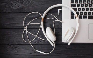 White headphone and laptop computer on wooden background.