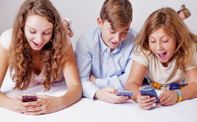 Game addiction concept. Group of friends smiling and gaming on smart phones and mobile devices.