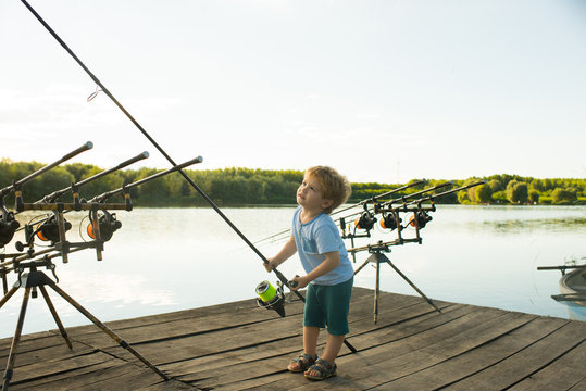 Angling child with fishing rod on wooden pier